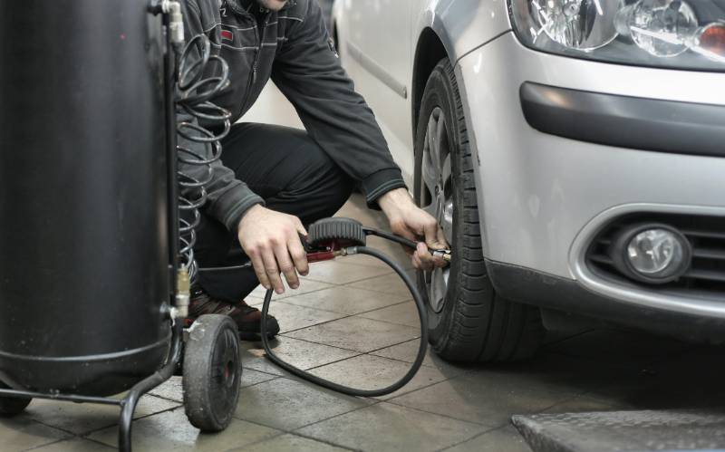A car tyre being inflated in a garage using a workshop tyre inflator