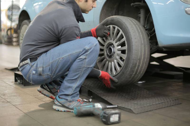 A man in a workshop removes a car's wheel