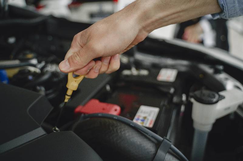 Driver checking car dipstick to see when to top up engine oil