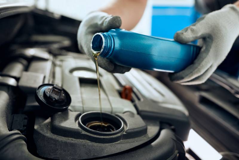 Pouring new engine oil into a car engine during oil change