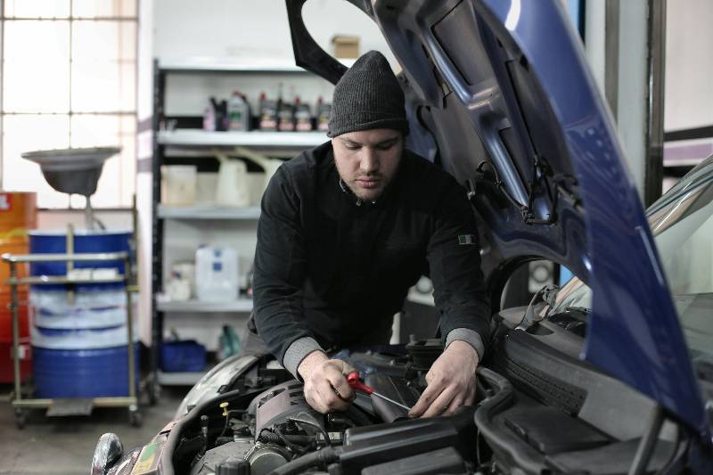 Mechanic checking dipstick under car hood