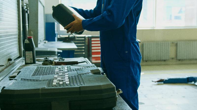 Mechanic holding oil container in workshop